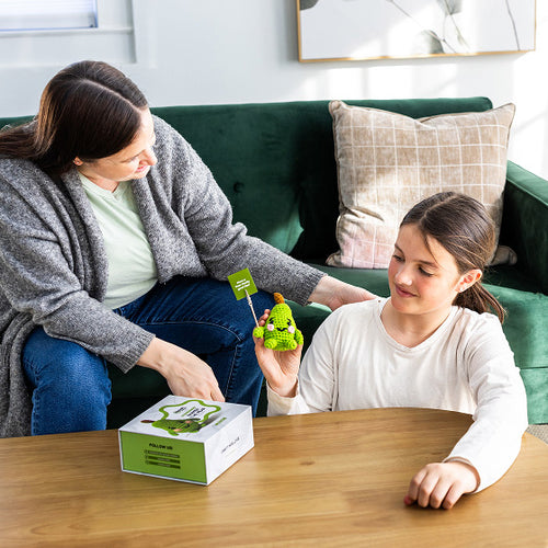 Woman and young girl sitting on a couch with a green toy 