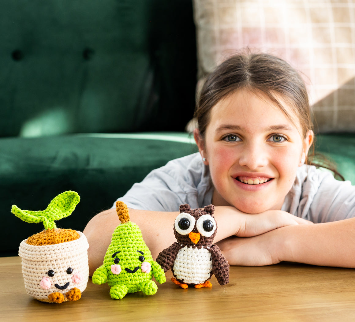 Young girl with three crocheted animals on a wooden surface