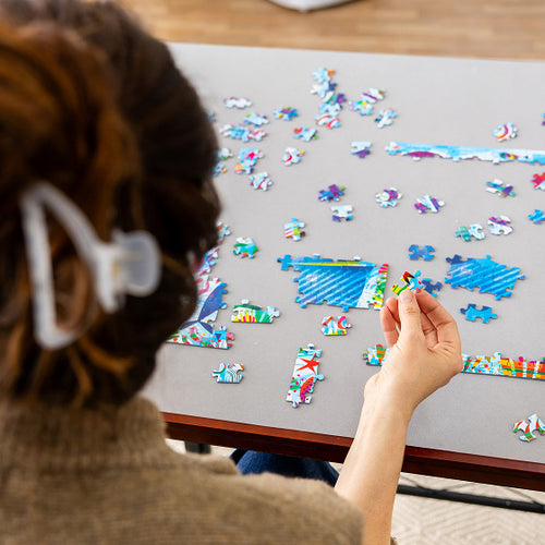 Person working on a puzzle with colorful pieces on a table